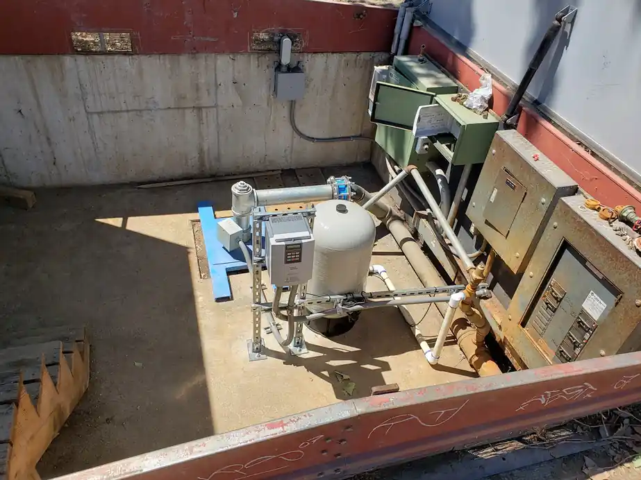 A pump vault seen from above with a pressure tank, VFD panels and controls