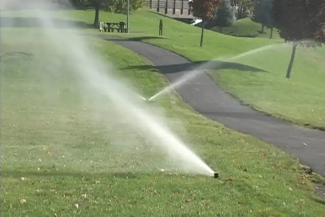 Sprinklers running across a grassy slope beside a path
