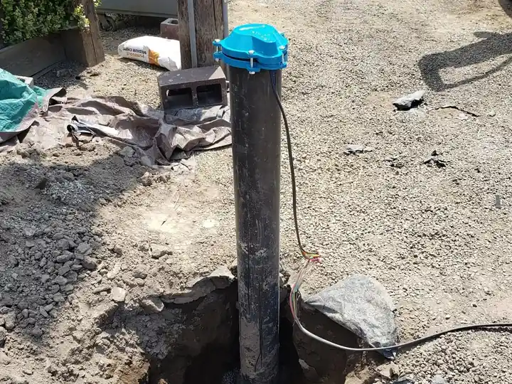 A well casing with a pitless cap set in an open trench