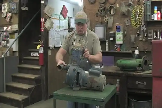 A technician at the repair bench working on an electric motor and pump