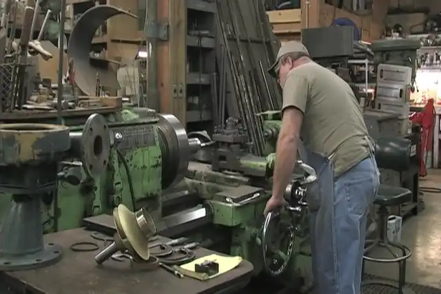 An Akland machinist at the big green lathe in the pump repair shop